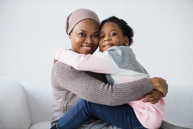 Daughter hugging mother while sitting on couch