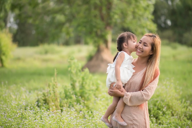 笑顔の母親のにキスをする娘が木に寄り添っている