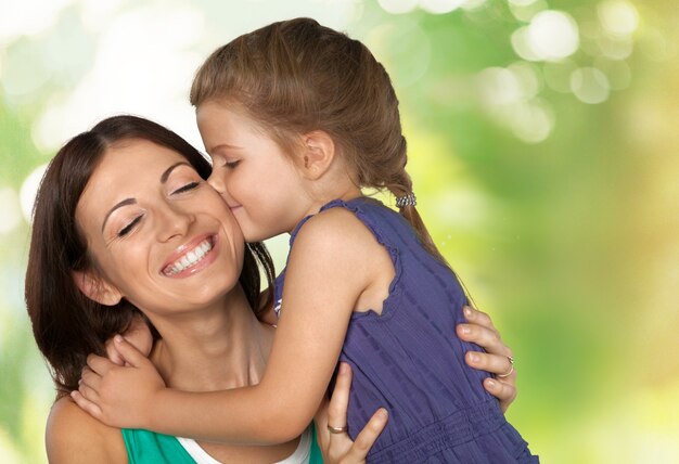 Daughter kissing mother  in bright bedroom