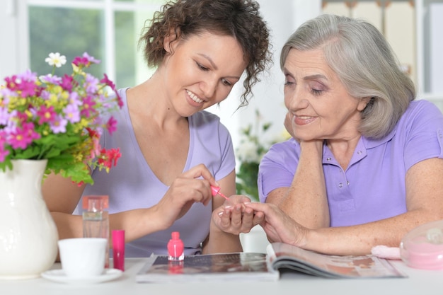 Daughter  making manicure to her mother, painting nails