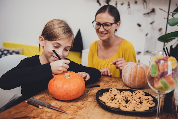 Daughter and mother creating Jack-O-Lantern