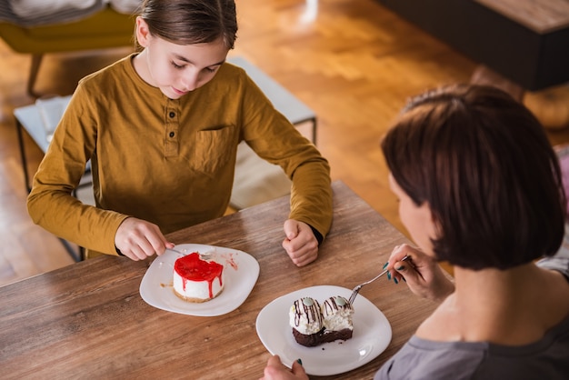 Daughter and mother eating cake at home