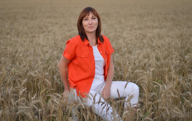 a daughter and a mother in a field with wheat are smiling and talking carelessly