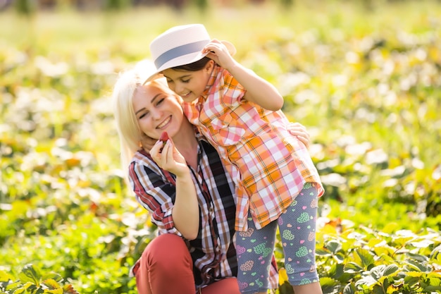 daughter and mother is working in the vegetables garden, harvested strawberries