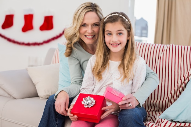 Daughter opening christmas gift with mother