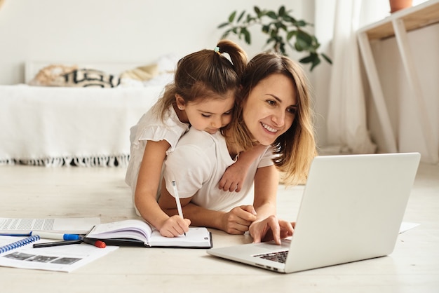 Daughter plays with mom and cat while mom works on computer