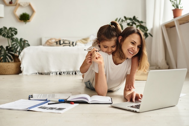 Daughter plays with mom and cat while mom works on computer