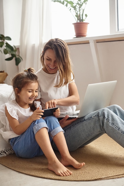 Daughter plays with mom and cat while mom works on computer