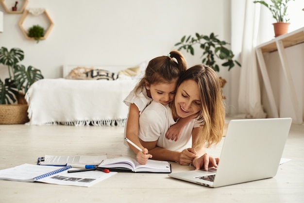 Daughter plays with mom and cat while mom works on computer