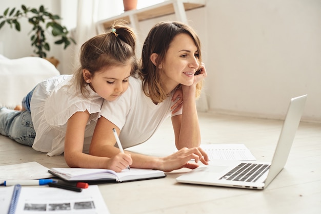 Daughter plays with mom and cat while mom works on computer