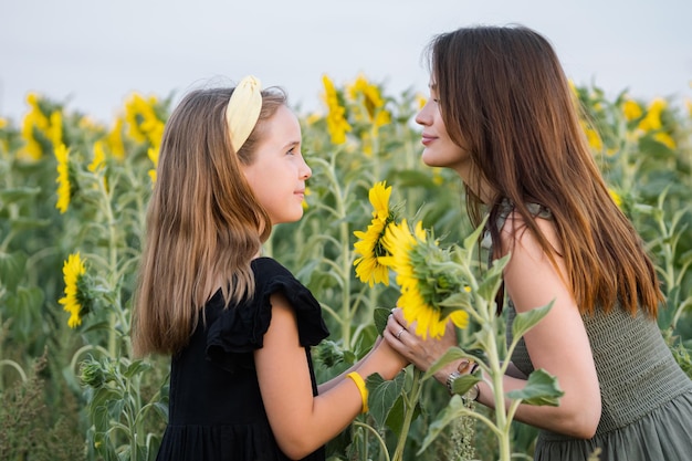 La figlia che riceve il girasole abbraccia la madre felice sul campo