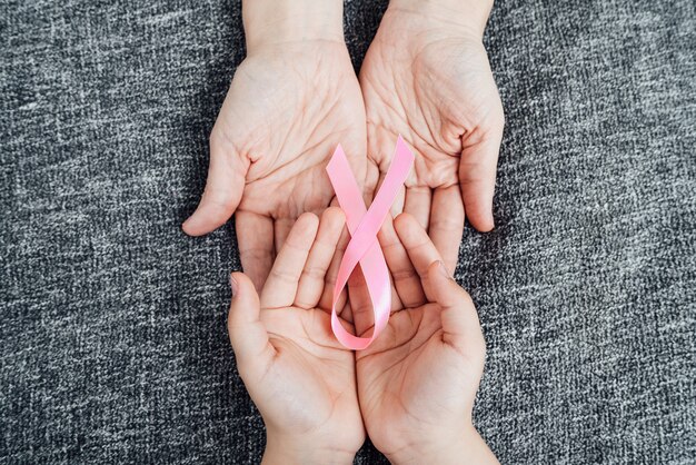 Le mani della figlia e della madre con il nastro rosa del cancro sui palmi