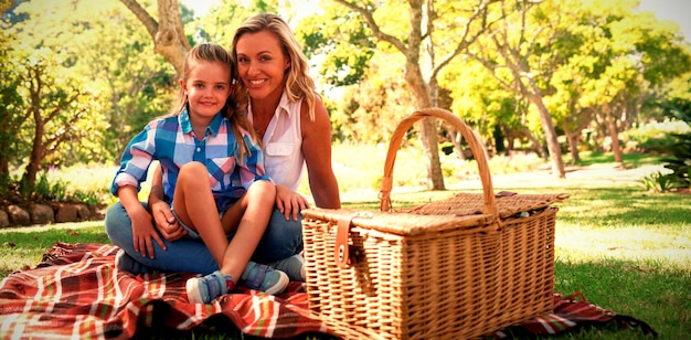 Photo daughter sitting on mothers lap while having picnic