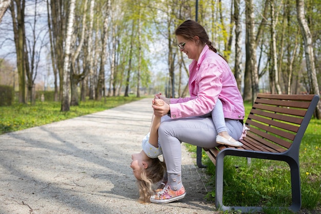 Photo the daughter tilts her head completely down and the mother belays the little gymnast