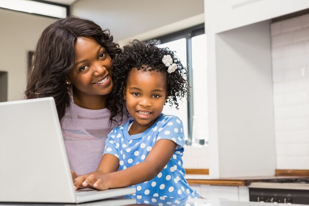 Daughter using laptop with mother in the kitchen 