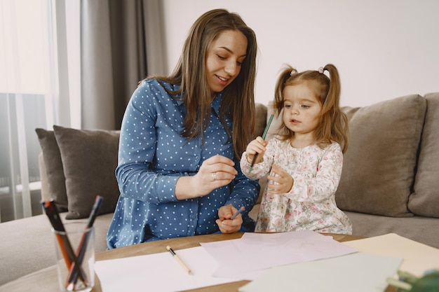 Figlia con fiori. mamma incinta sul divano. madre e figlia in abiti luminosi.