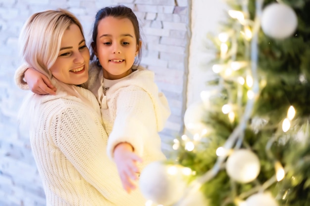 Daughter with her mother near the Christmas tree.