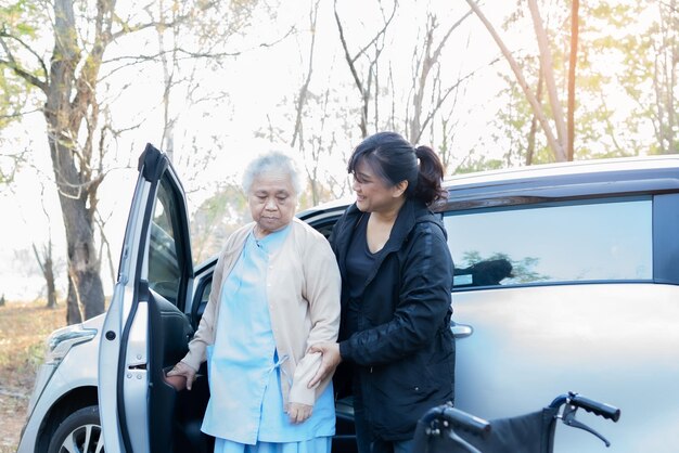 高齢の母親と一緒に車のそばに立っている娘