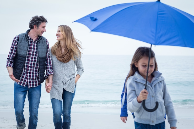 फोटो daughter with umbrella while parents walking at sea shore