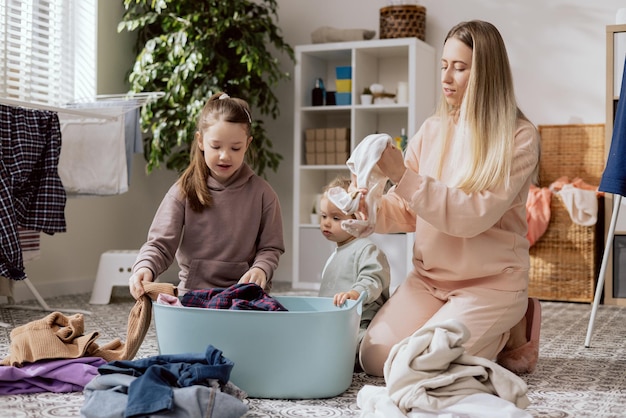 Daughters help mom with household chores women sort laundry fold clothes