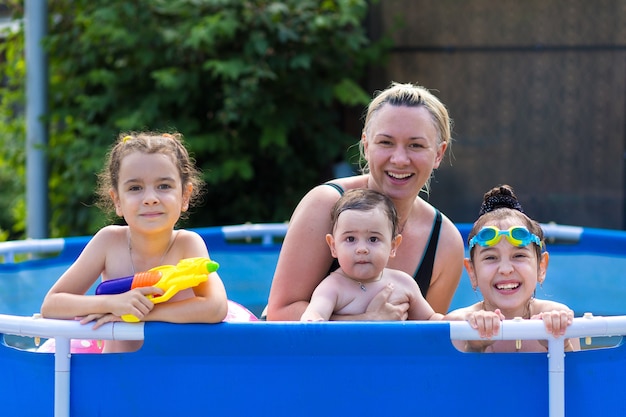 Daughters and mother family swimming in pool on summer vacation