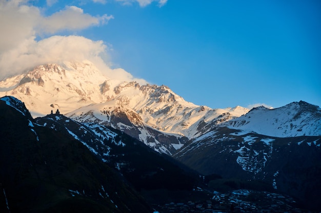 Alba in montagna i raggi del sole cadono sulla cima del monte kazbek una mattina stimolante per il viaggiatore