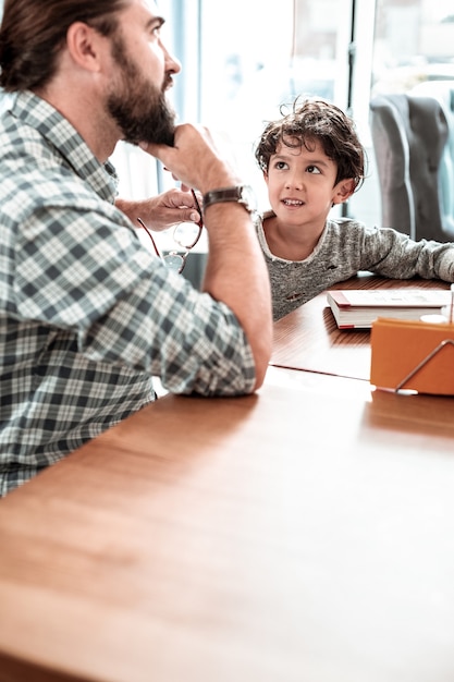 day together. bearded dad and cute son feeling happy spending day together sitting in restaurant