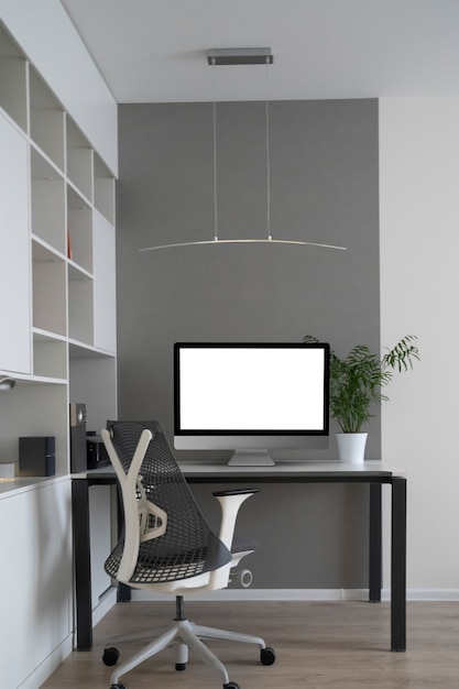 Daylight interior with white modern computer monitor in an office table, orthopaedic chair, and greenery pot