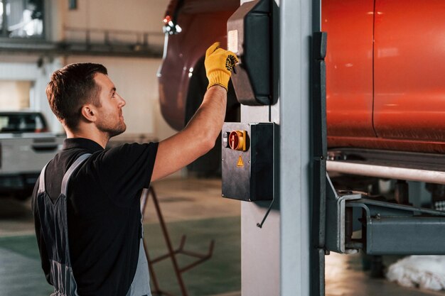 At daytime Man in uniform is working in the auto service