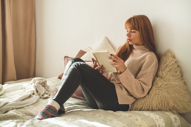 De aantrekkelijke jonge vrouw leest thuis een boek