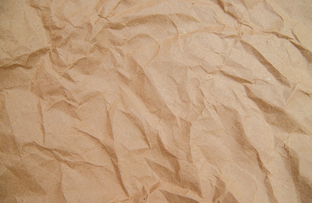 De achtergrond en textuur zijn gemaakt van verfrommeld beige kraftpapier. Inpakpapier voor pakjes en cadeaus. Een lege ruimte voor de tekst.