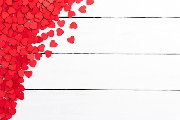 De achtergrond van de valentijnskaartendag, klein houten rood hart op witte achtergrond.
