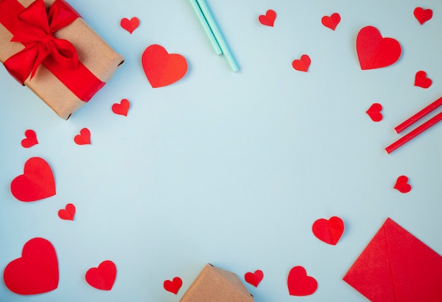 De achtergrond van valentijnsdag. geschenken, harten, cocktailbuizen, lint in pastelblauw. het concept van valentijnsdag. bovenaanzicht, kopie ruimte