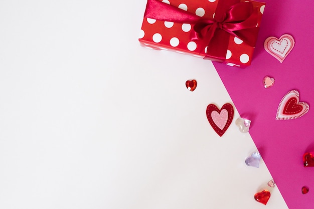 De achtergrond van valentijnsdag. rode geschenkdoos met rood satijnen lint en veel verschillende harten