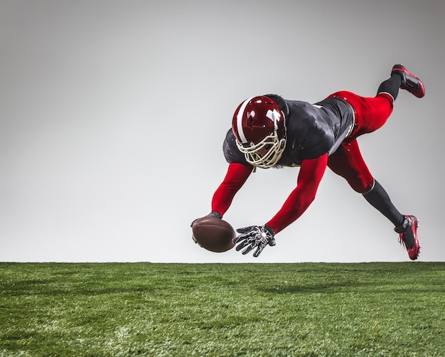 De american football-speler in actie op groen gras en grijze achtergrond.