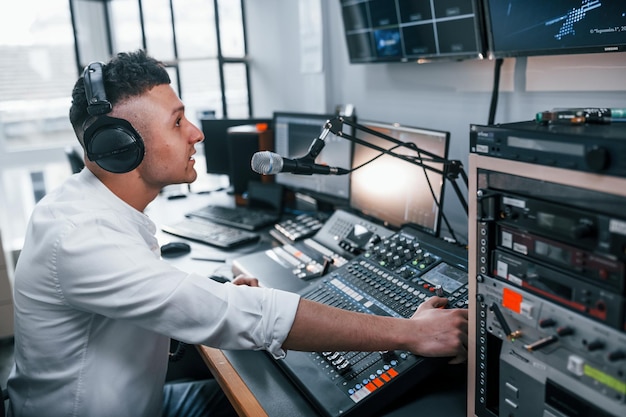 De apparatuur instellen Jonge man is binnen in de radiostudio is bezig met uitzending