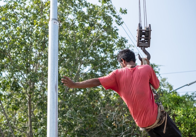 De arbeider hangt op kraanwagen om elektrische pool te herstellen.