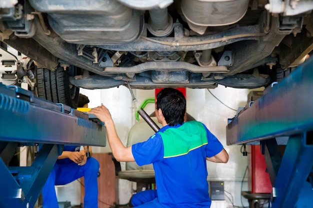De arbeider herstelt een auto in een autoreparatiecentrum