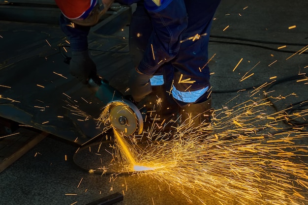 De arbeider snijdt een plaat metaal met een slijper Vlieg heldere vonken Werkproces in de winkel in de fabriek