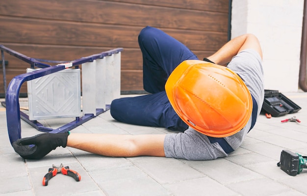 De arbeider viel van de ladder terwijl hij in de buurt van het huis aan het werk was