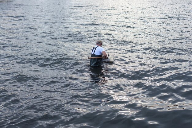 De arbeider zoekt iets in het water, vangt verschillende voorwerpen op