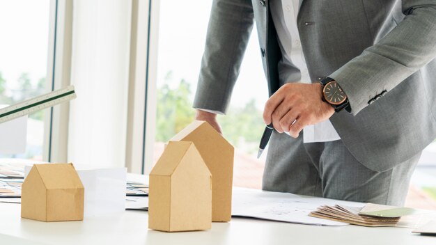 De architectuur van de blauwdruktekening met conceptueel de bouwmodel en materiaal op het bureau.