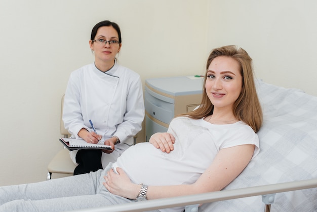 De arts adviseert en bedient een jong zwanger meisje in een medische kliniek. geneeskundig onderzoek