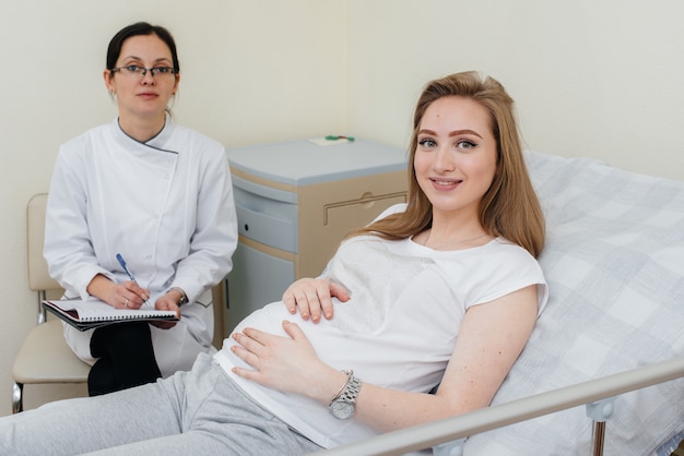 De arts adviseert en bedient een jong zwanger meisje in een medische kliniek. geneeskundig onderzoek