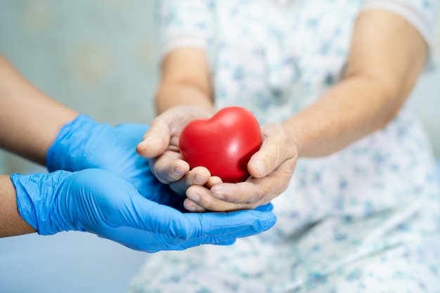 De arts geeft rood hart aan Aziatische hogere vrouwenpatiënt met liefde