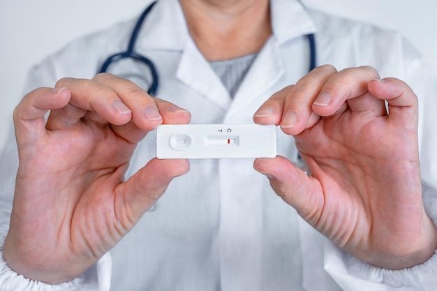 De arts houdt een uitdrukkelijke testcassette voor hepatitis of coronovirus in handen