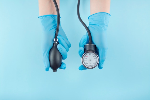 Foto de arts houdt in zijn handen een medisch apparaat om bloeddruk op een blauwe achtergrond te meten. medische achtergrond. het medicijn. kopieer ruimte.