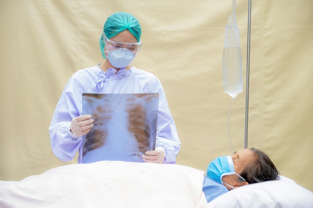 de arts legt de resultaten van de longröntgenfoto uit aan een oudere patiënt die op het bed ligt