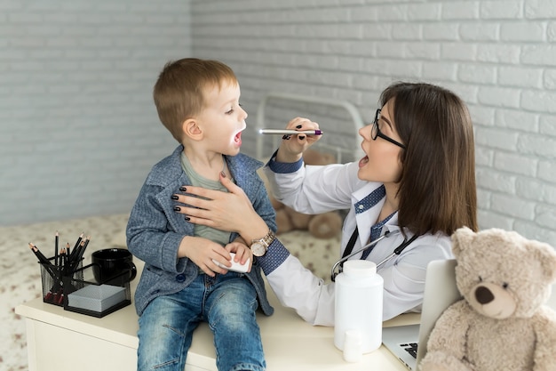 De arts onderzoekt de keel van het kind. Jongen bij kinderarts kantoor.