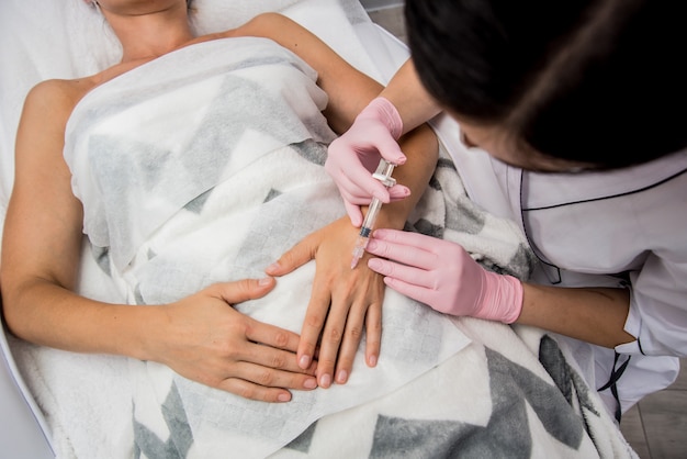 De arts-schoonheidsspecialist maakt de procedure voor het injecteren van armen.